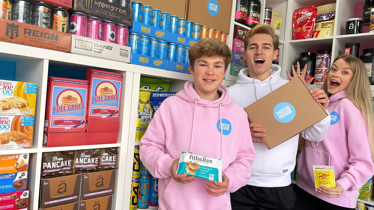 The store owner standing with two teammates in pirk shirts and holding their products